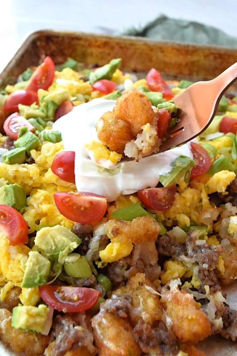 A spoonful of totchos over a plate of them