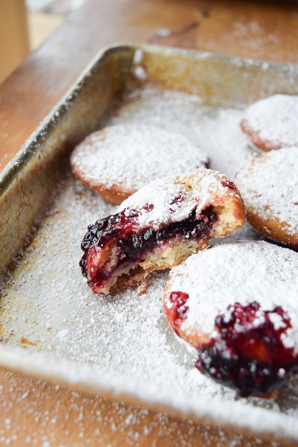 Gluten free black raspberry jelly doughnuts freshly baked on a baking sheet.