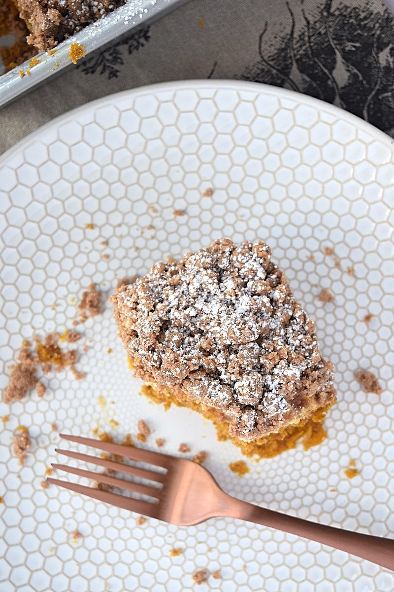 A piece of pumpkin coffee cake with a bite taken out of it.