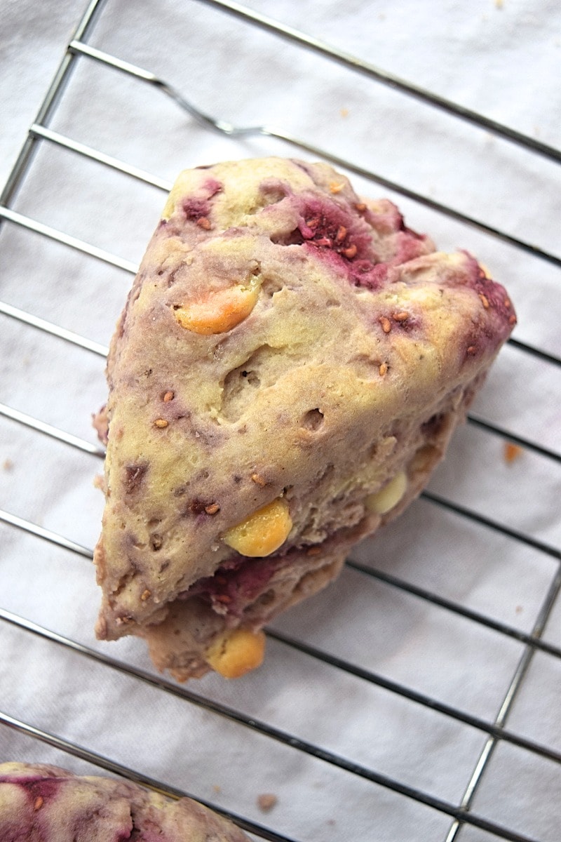 Cover image for gluten free raspberry white chocolate scones - features a single scone cooling on a baking rack