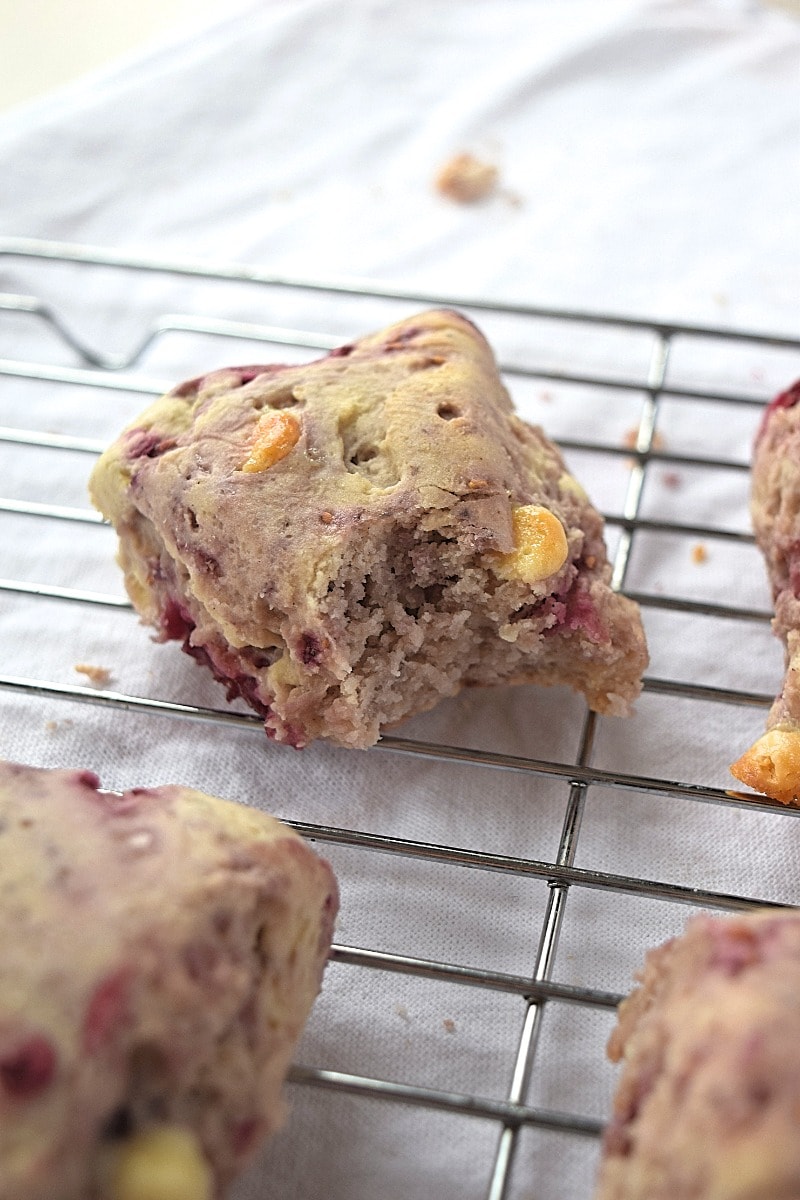 A bite taken out of a gluten free raspberry white chocolate scone.