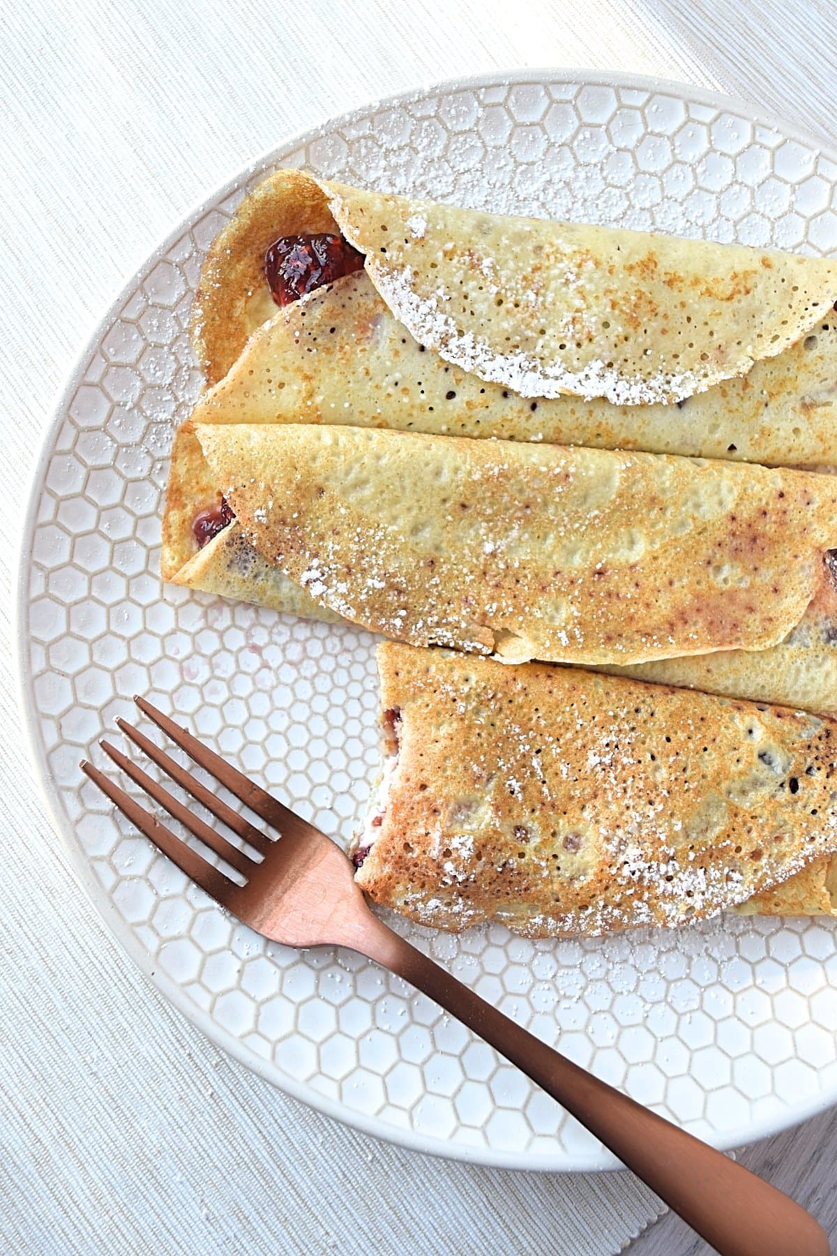 A fork sitting on a plate with gluten free blintzes