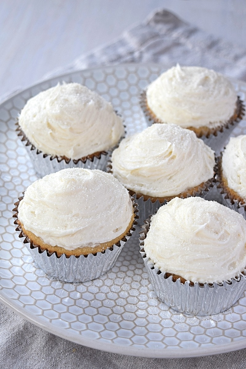 Cover image for gluten free vanilla cupcakes post - features fresh-baked vanilla cupcakes on a white plate.