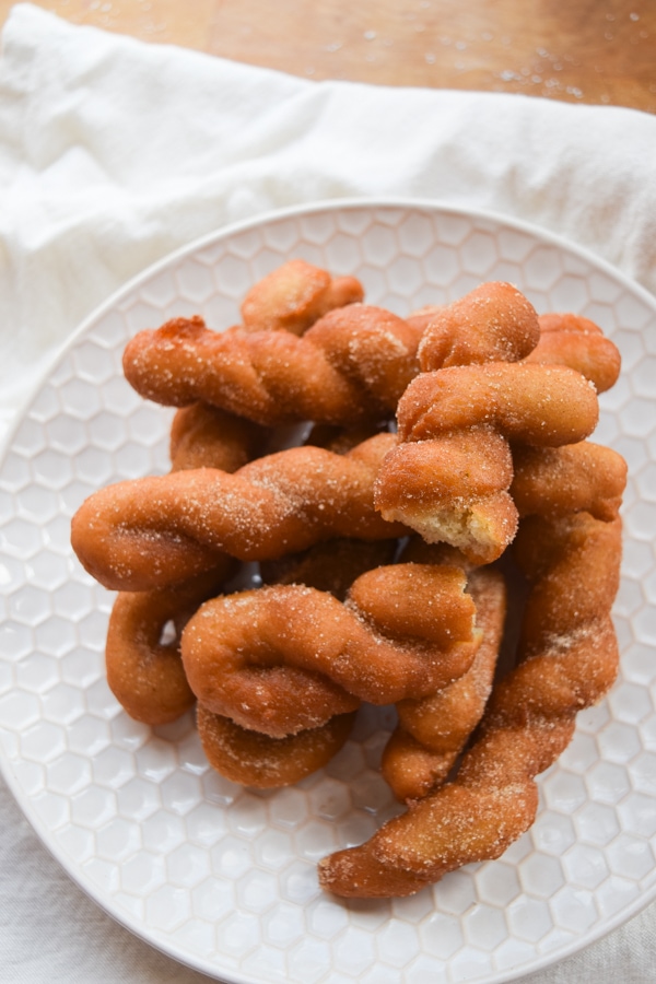 Cover image for Gluten Free Cinnamon Twists blog post. Features a pile of freshly baked cinnamon twists on a white plate.