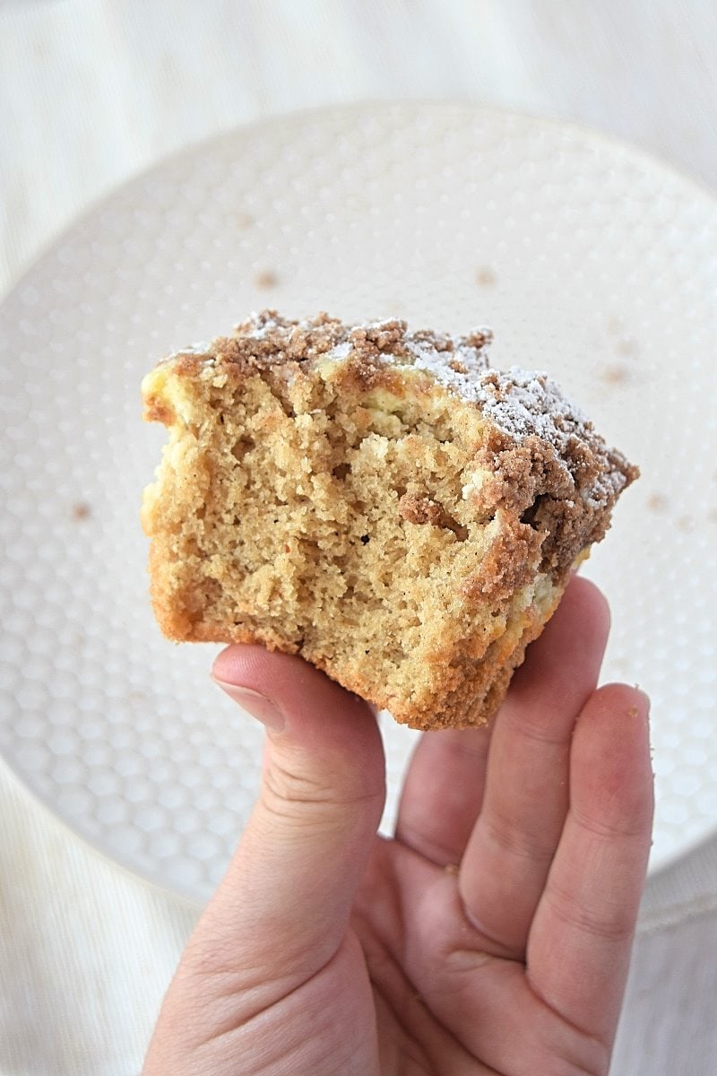 Holding up a gluten free coffee cake with a bite missing out of it