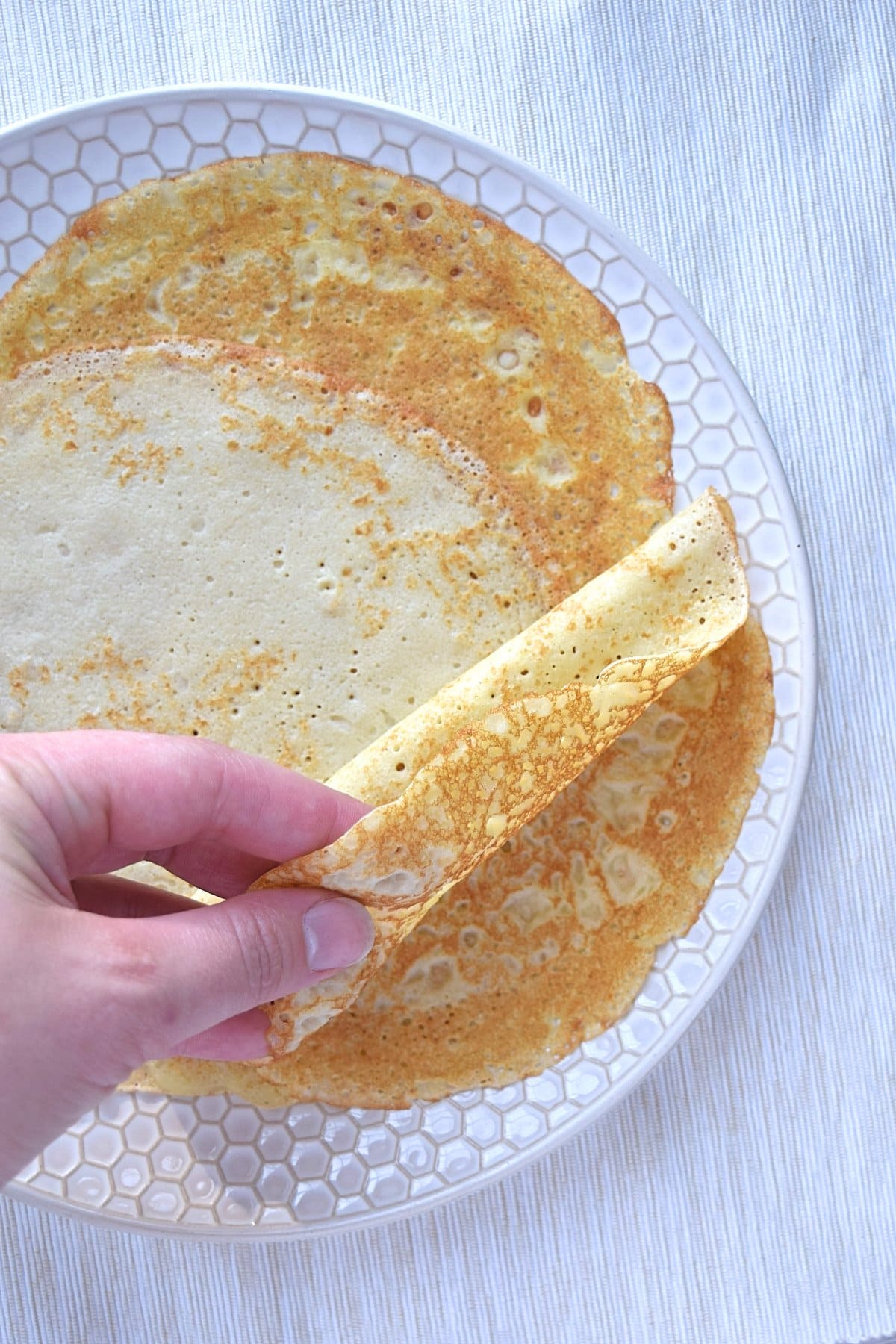 Folding a crepe on top of a plate of crepes.