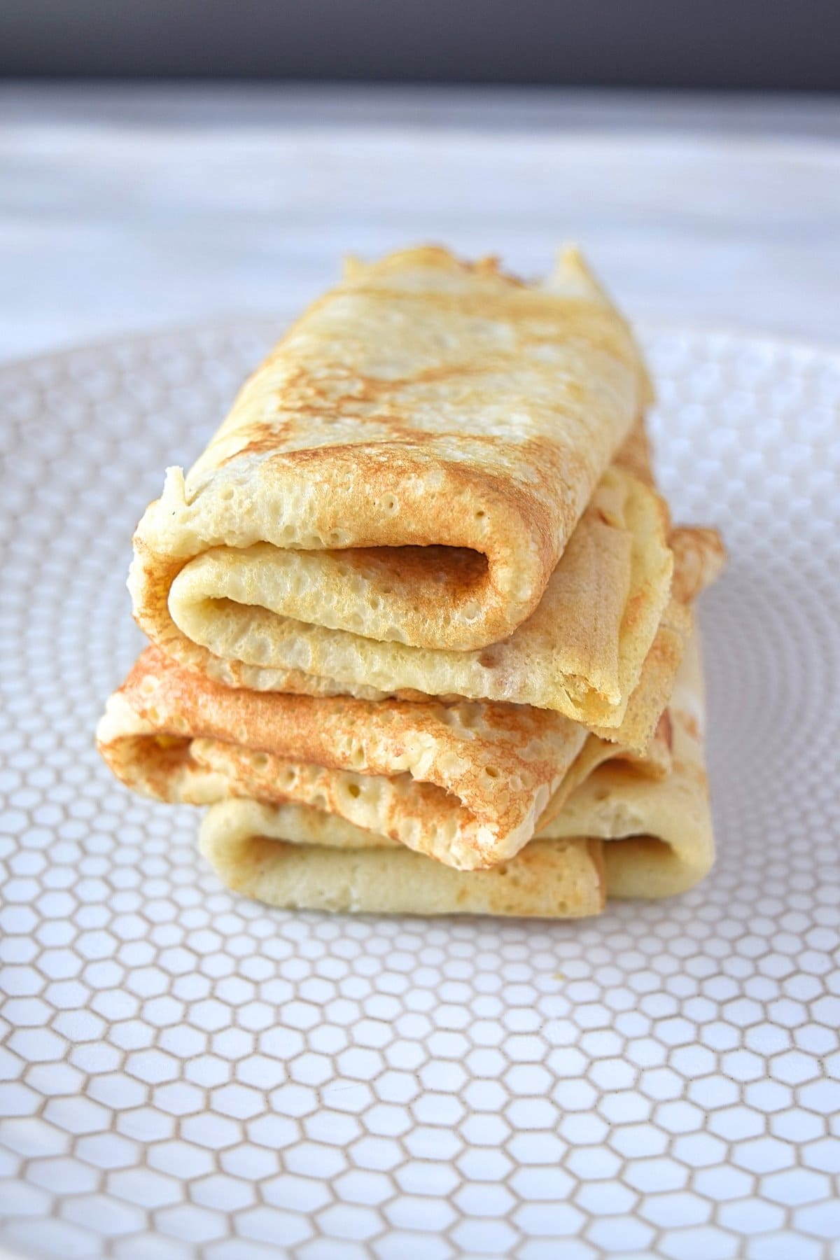 A stack of folded crepes sitting on top of a white plate.