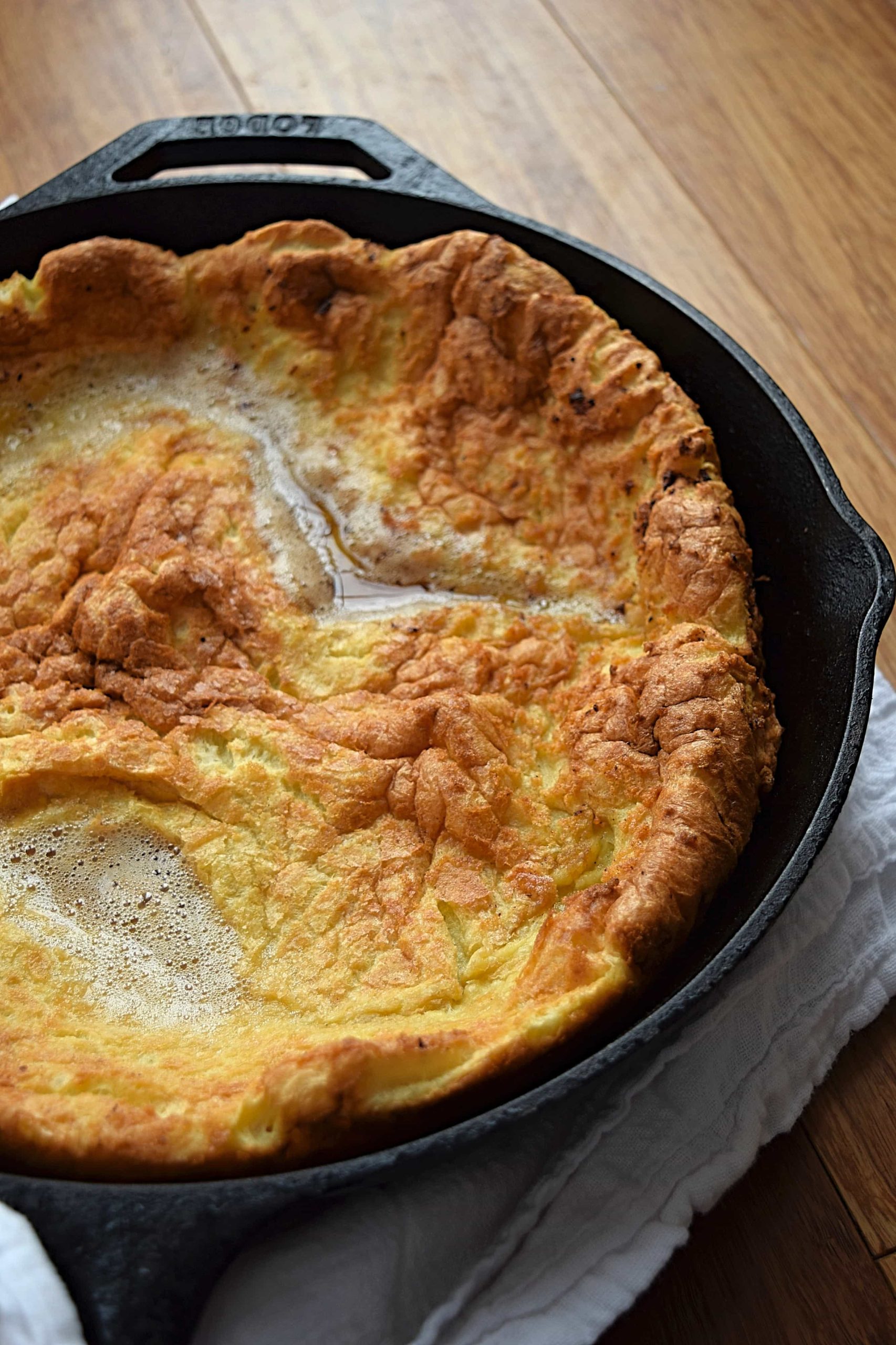 A close up image of a gluten free dutch baby in a cast iron pan