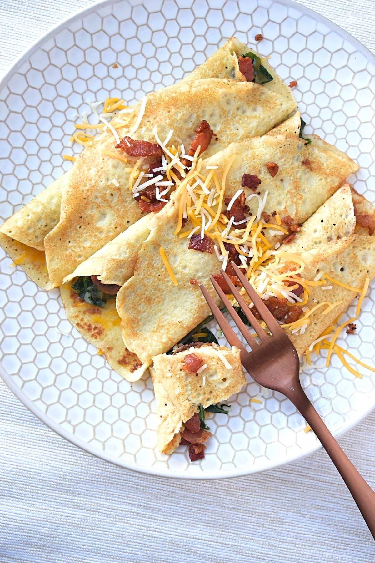 A fork sitting on a plate with 3 savory crepes