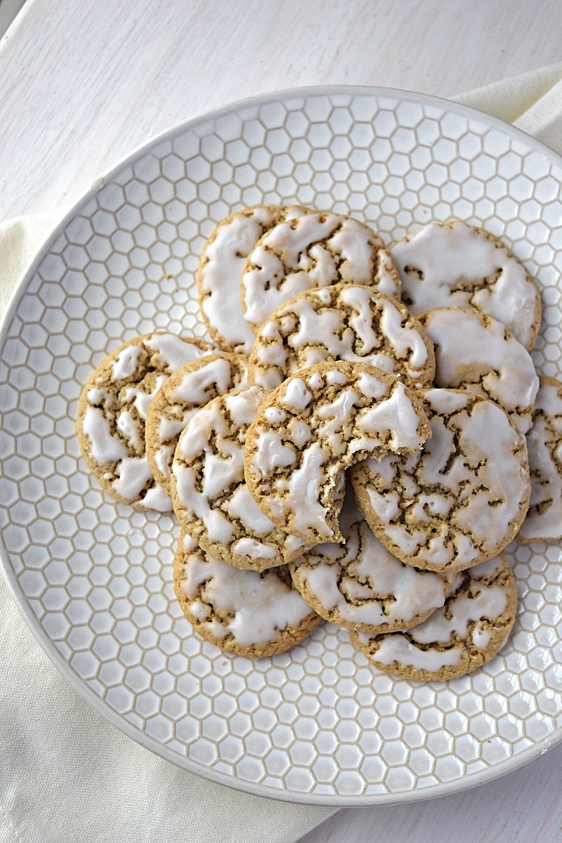 An overhead plate of old fashioned oatmeal cookies, a bite has been taken out of one of the cookies.