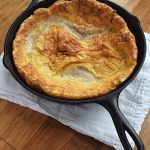 Cover image for gluten free dutch baby blog post. Features a freshly cooked German pancake in a cast iron pan.