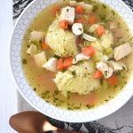 a bowl of gluten free chicken dumpling soup with a spoon