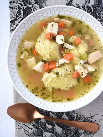 a bowl of gluten free chicken dumpling soup with a spoon